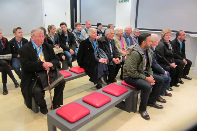 A group of people sitting down and listening to thew guide