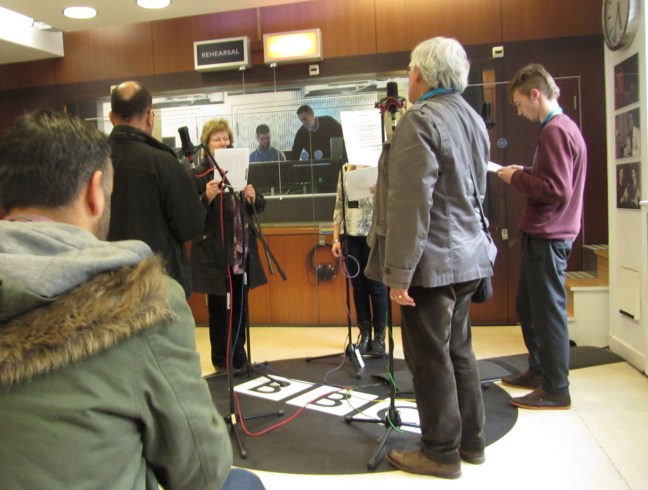 People standing in a circle facing microphones